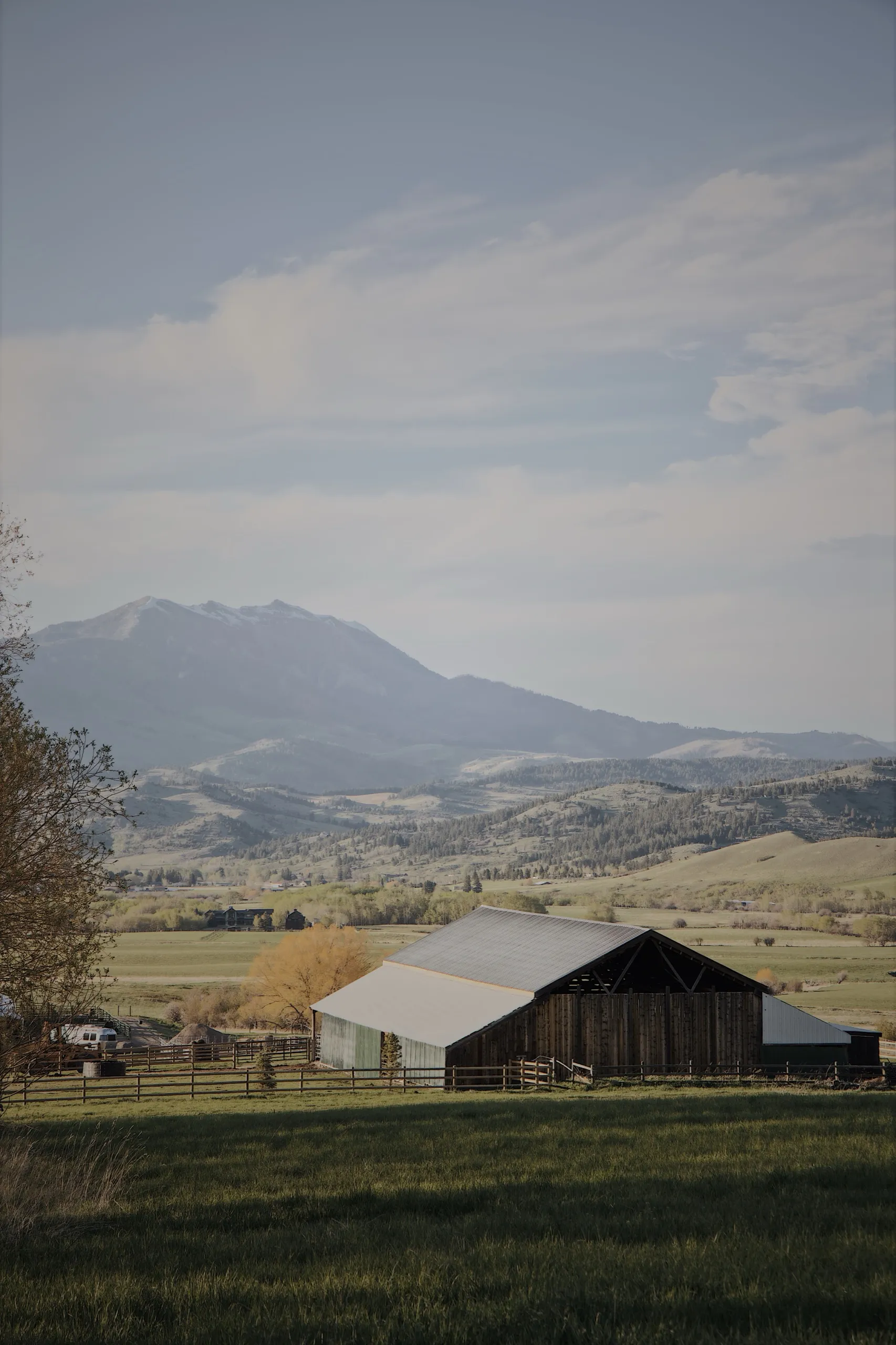A weathered barn in open pasture, the mountains beyond